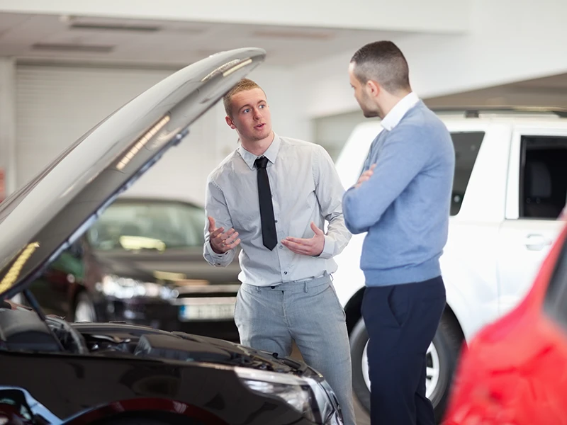 Zwei Männer stehen an einem Auto mit geöffneter Motorhaube: Unfallwagen erkennen