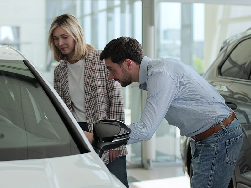 Paar schaut von außen in ein Auto: Fahrzeughistorie prüfen vor dem Gebrauchtwagenkauf