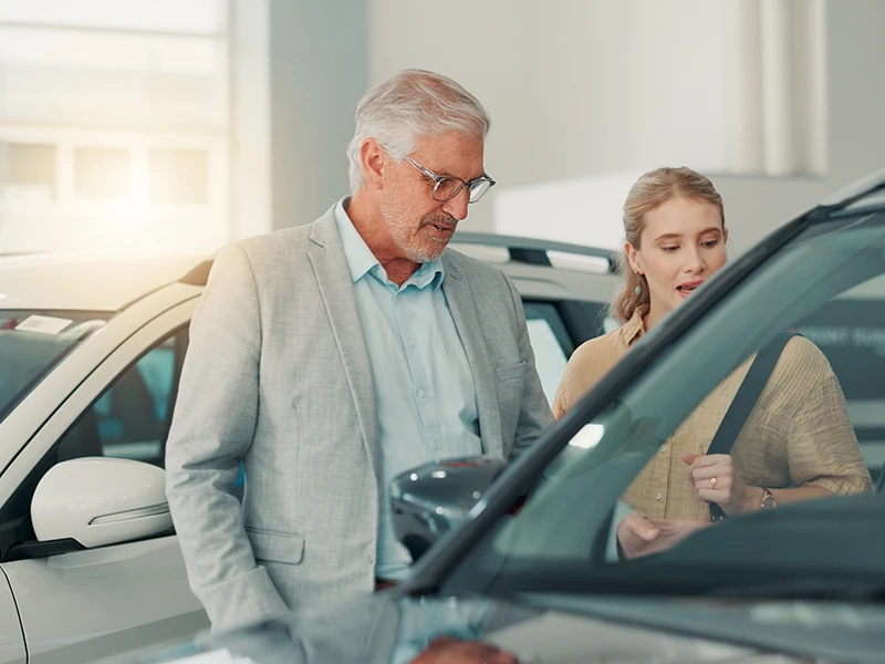 Mann und Frau betrachten gemeinsam ein Auto: Kilometerstand vor dem Kauf auf Tachomanipulation prüfen